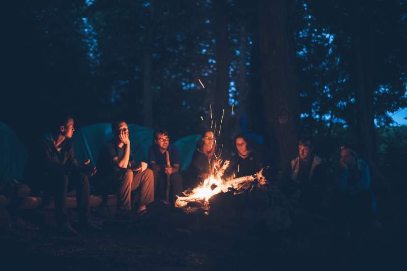 a group of friends sitting by a campfire