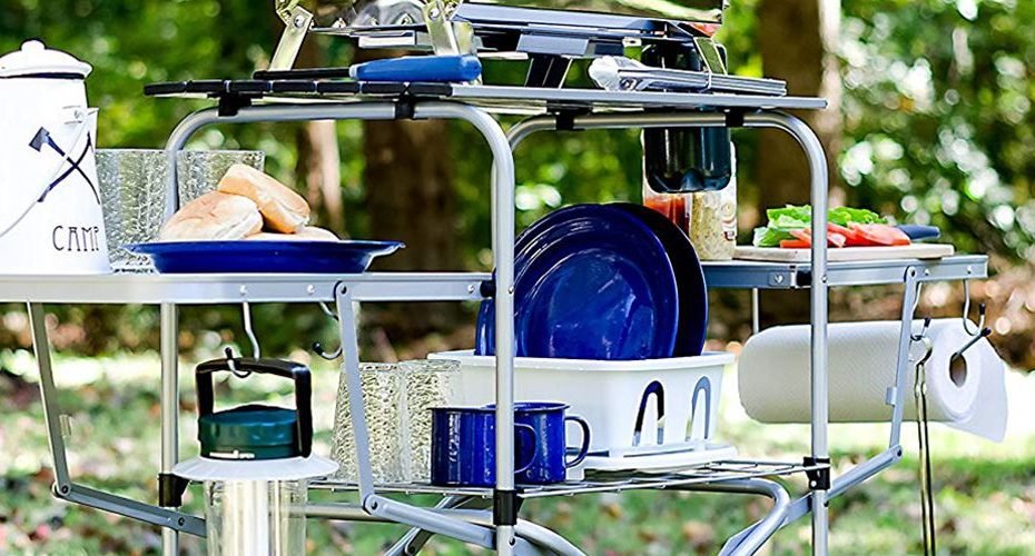 a camping grill table full of utensils and cooking accessories