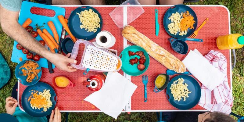 a camping table covered in cooking utensils and food 